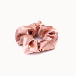 Close-up of pink crystal satin scrunchie with smooth silk texture and ruched design