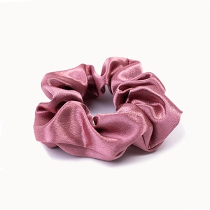 Close-up of pink satin scrunchie with silky luster texture and soft elastic band