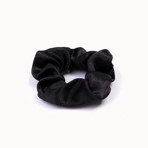 Detailed view of a black satin scrunchie with smooth texture and glossy finish