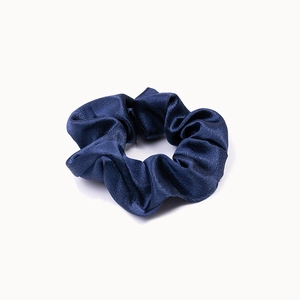 Close-up of a navy blue crystal satin scrunchie showing glossy silk texture and folds