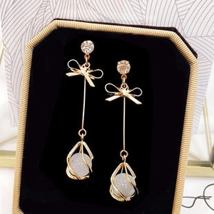 Detail of gold butterfly tassel earring with crystal and cat eye stone in a jewelry box