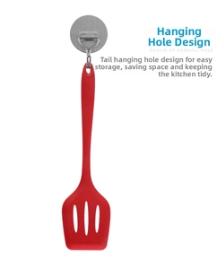 Detail of red silicone slotted turner with hanging hole design on white background