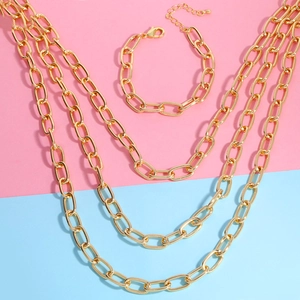 Set collana e bracciale a catena grossa dorata su sfondo bicolore in stile moderno
