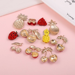 DIY metal fruit charms including pineapple and cherry on a pink decorative background