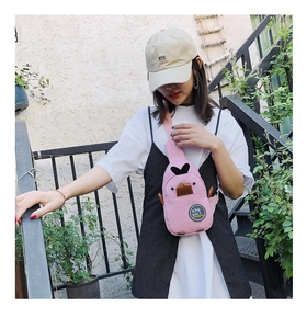 Pink cartoon duck canvas chest bag shown on a model in an outdoor casual street setting