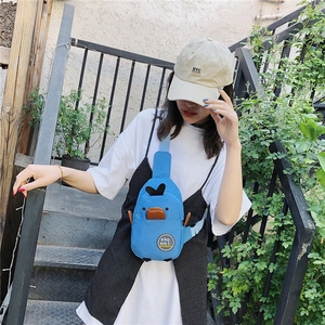 Outdoor detail shot of a sky blue canvas crossbody bag featuring a cartoon duck design