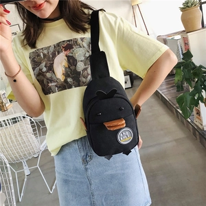 Detail of cute penguin canvas crossbody bag with 3D wings and round logo patch