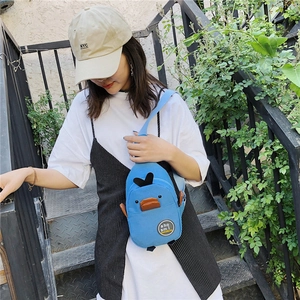 Blue canvas crossbody bag with cartoon duck design worn by model on outdoor stairs