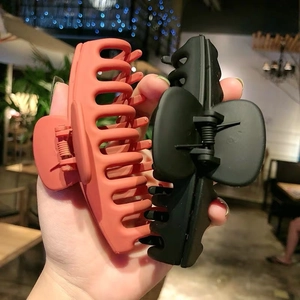 Close-up of large plastic shark hair clips in orange and black held in hand