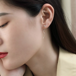 Close-up of minimalist S925 sterling silver wave drop earrings on a model's ear