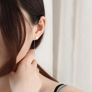 Close-up of S925 sterling silver heart stud earrings with long tassel chain on model ear