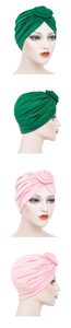 Detail view of emerald green and light pink turban caps with elegant rose knot designs