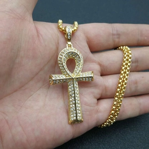 Nahaufnahme eines goldenen ägyptischen Ankh-Anhängers mit Kristallen in einer Hand