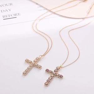 Macro detail of gold cross pendants with white and pink cubic zirconia on fine chains