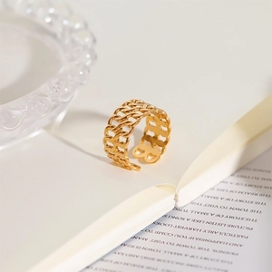 Close-up of gold hollow woven chain ring on an open book in a warm indoor setting