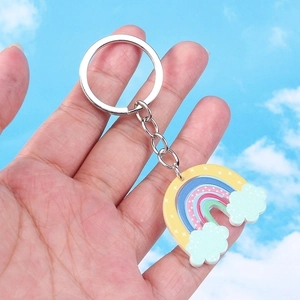 Rainbow and clouds acrylic keychain with silver metal ring against a clear blue sky