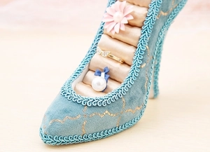 Detail of blue velvet high heel ring holder with gold embroidery and soft foam slots