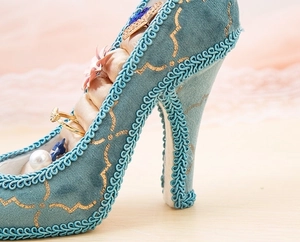 Close-up of light blue high heel ring holder with gold embroidery and lace trim detail