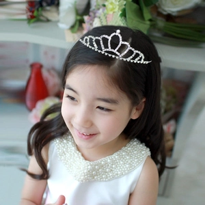 Detail view of a little girl wearing a sparkling silver tiara with crystal rhinestones