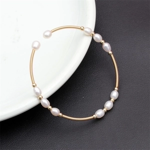 Macro shot of colorful natural freshwater pearls on a gold elastic wire cuff bracelet