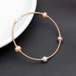Detail of copper wire wrapped bracelet with white and pink pearls on black leather