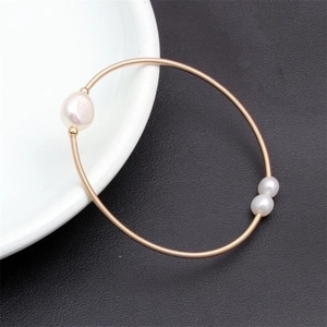 Macro shot of gold wire-wrapped bracelet featuring three elegant freshwater pearls