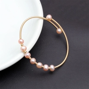 Detailed macro shot of multi-layer woven pink pearl bracelet with gold wire accents