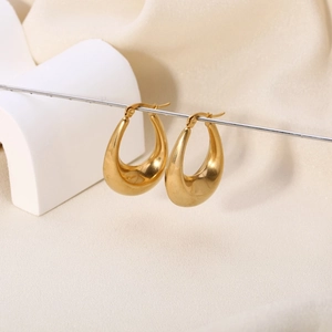 Detailed close-up of chunky gold-plated teardrop earrings with a smooth polished finish