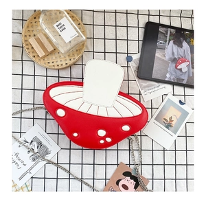 Top view of red mushroom crossbody bag with white dots and silver metal chain strap