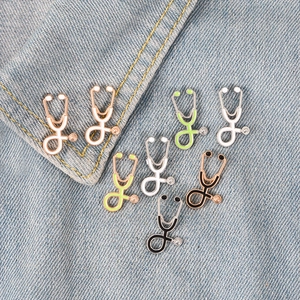 Close-up of assorted stethoscope enamel pins in five colors on blue denim fabric
