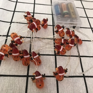 Detailed close-up of festive reindeer LED string lights with clear battery box on plaid background