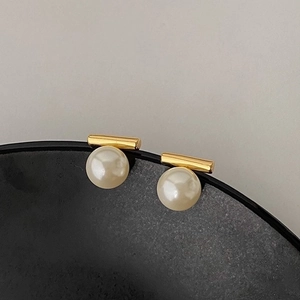 Minimalistische Goldstab Perlenohrringe an schwarzem Keramikrand präsentiert