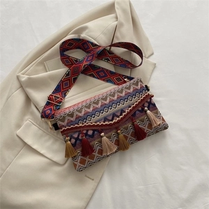 Detail of woven bohemian handbag with colorful geometric patterns and long tassels