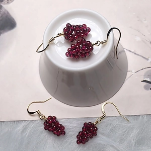 Close-up of handmade garnet grape earrings with burgundy beads and gold hooks