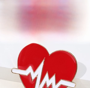Detail of red enamel heart brooch with white heartbeat pulse line on gold metal base