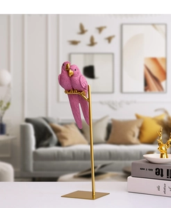 Detail of pink resin parrot figurines with textured feathers and gold metal base