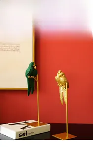 Detail of Nordic parrot resin statues on gold stands against a red background