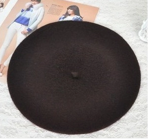 Detailed top view of black wool beret on fashion magazine and white lace background