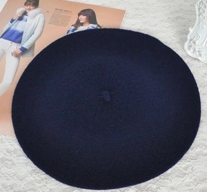 Top-down view of navy blue wool newsboy hat on a vintage magazine background
