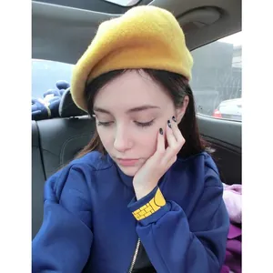 Fashionable solid yellow beret hat for women styled with a casual navy blue zipper jacket