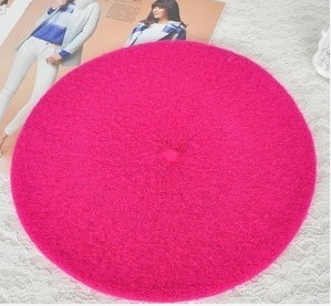 Flat lay of rose red wool beret on white lace fabric for autumn and winter style