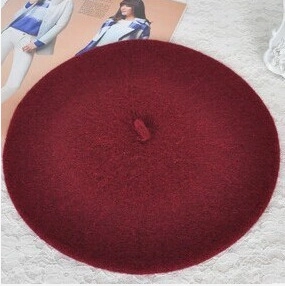 Flat lay view of a wine red wool beret on white lace texture for autumn and winter