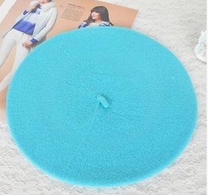 Detail view of lake blue beret hat in soft wool fabric on a vintage lace background