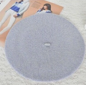 Detail of a grey wool felt beret hat placed over a stylish magazine and white lace