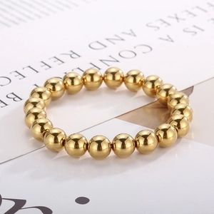 Macro shot of high-polish gold ball bead elastic bracelet on minimalist white display card