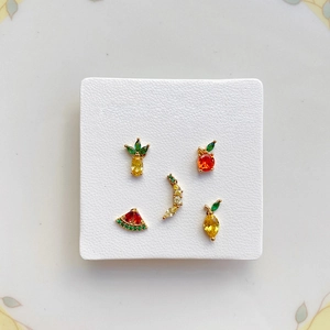 Close-up of five-piece fruit stud earring set featuring pineapple and watermelon designs