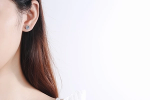 Close-up of sparkling round six-prong moissanite stud earring worn on a model's ear