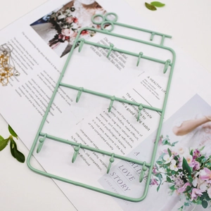 Light green metal jewelry organizer rack with multiple hooks on a stylish magazine