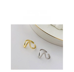 Makroaufnahme minimalistischer, wellenförmiger offener Ringe aus S925 Silber in Gold und Silber