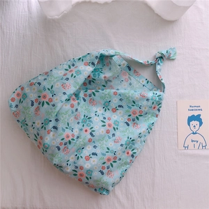Detail of light blue floral cotton tote bag with daisy print and knot bow strap